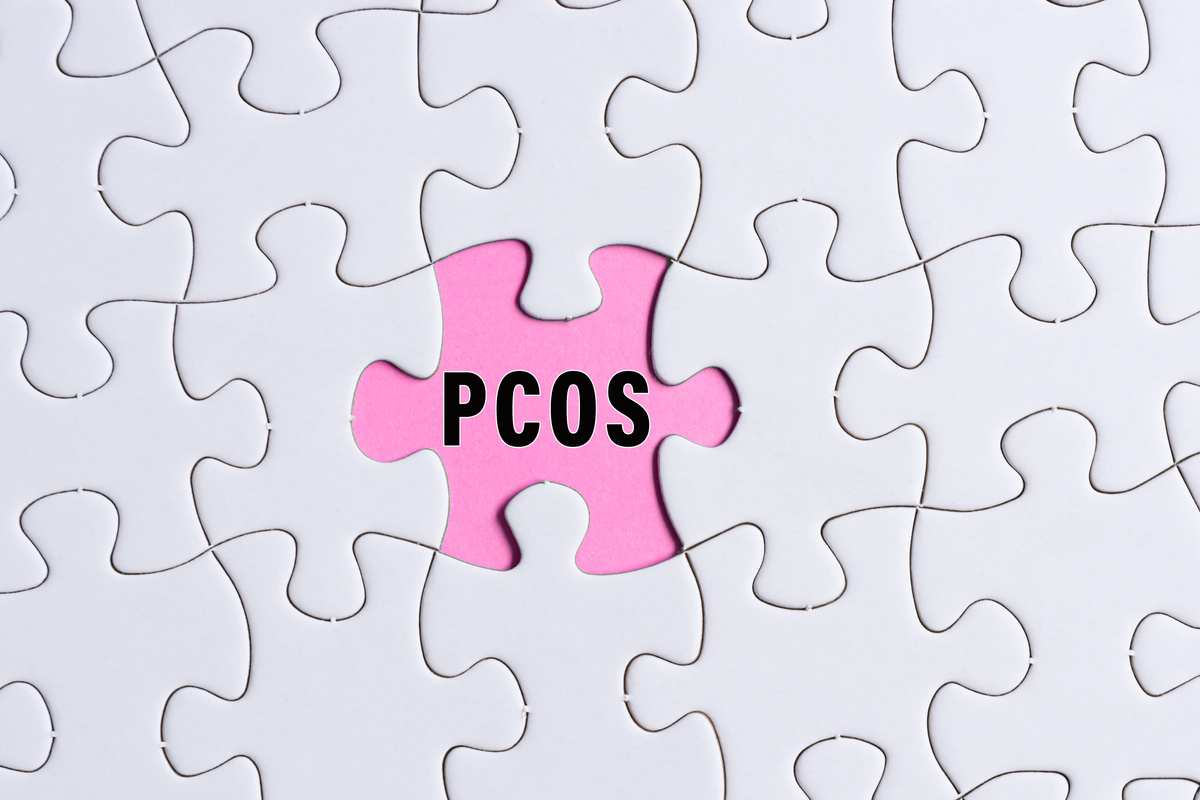 PCOS text on white jigsaw puzzle over pink background. Healt